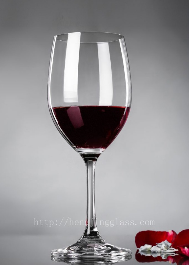 Stemmed red wine glass by Hengjing Glass on neutral background